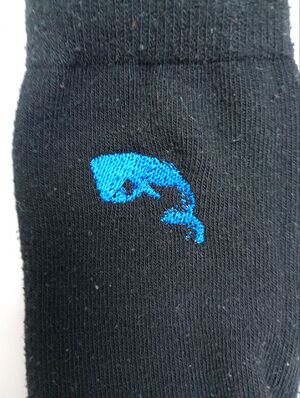 Second broderie d'un cachalot bleu sur une chaussette noire