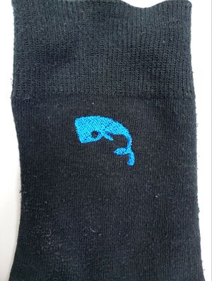 Troisième broderie d'un cachalot bleu sur une chaussette noire