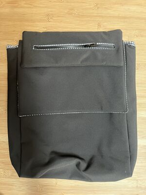 Sacoche noire rectangulaire avec abattant sur le dessus sur lequel une trousse extra-plate est accrochée
