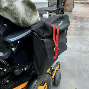 Saccoche accrochée au fauteuil fermée comme un cartable, avec une poche à fermeture éclaire